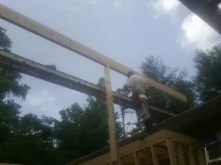 Carpenter setting a ridge beam over a new addition frame — Ice Dam Removal by Roofing Brothers in Cullowhee