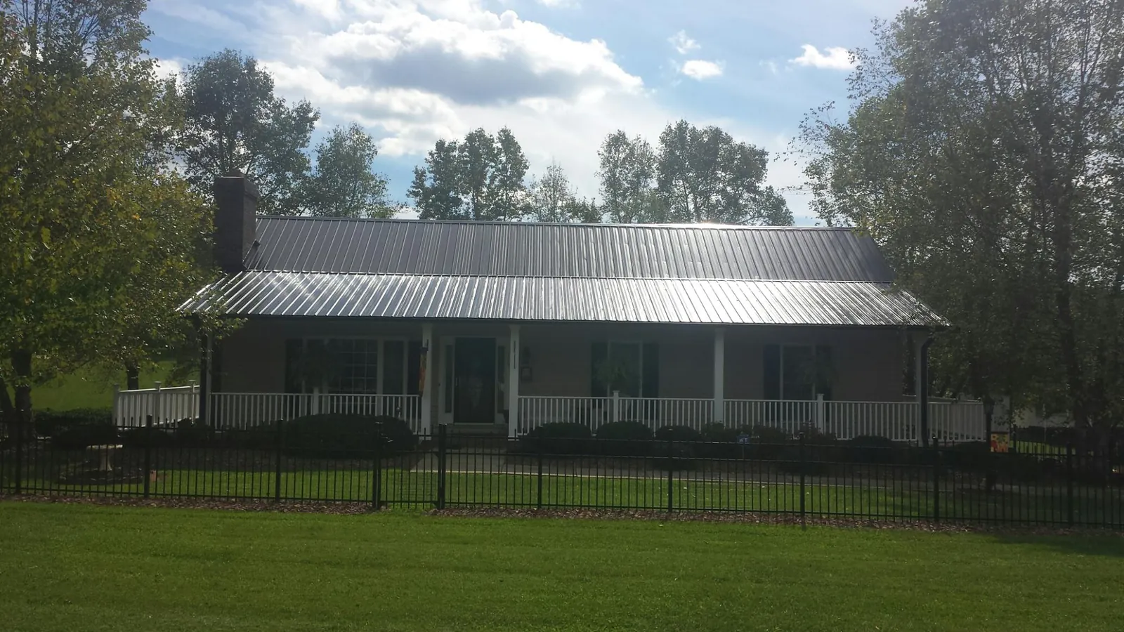 Gray metal roof on a brick ranch with a full width front porch — Gutter Guard Installation work by our crew in Cullowhee